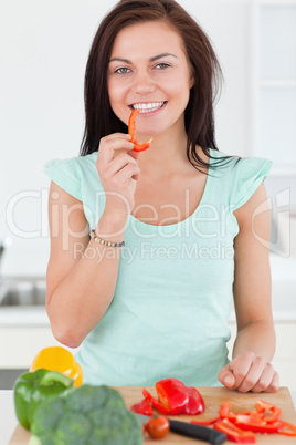 Portrait of a cute woman eating a slice of pepper