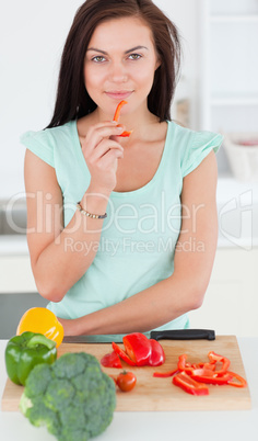 Portrait of a charming woman eating a slice of pepper