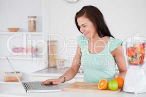 Woman with a laptop and fruits in a blender