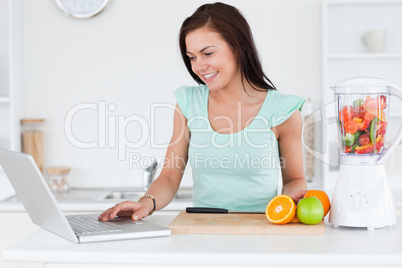 Young brunette with a laptop and fruits