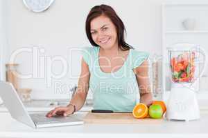 Cute brunette with a laptop and fruits