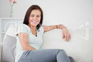 Close up of a smiling brunette onn a sofa looking at the camera