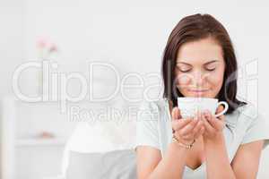Delighted dark-haired woman drinking tea