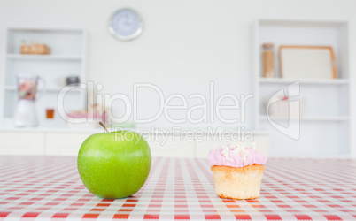 An apple and a cupcake on a tablecloth