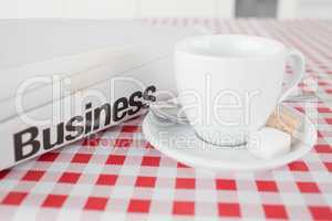 A cup of tea and a newspaper on a tablecloth