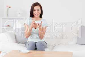 Smiling dark-haired woman drinking tea