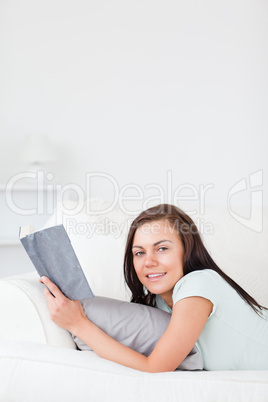 Charming woman on a sofa with a book