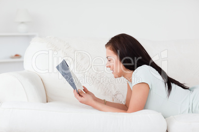 Close up of a woman on a sofa reading a book against a white background