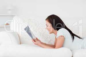 Close up of a woman on a sofa reading a book against a white background