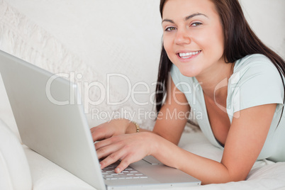 Close up of a smiling woman on a sofa using a laptop