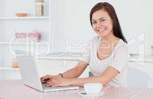 Brunette using her laptop and having a tea
