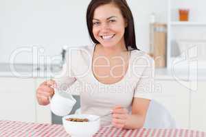 Young woman pouring milk in her cereal