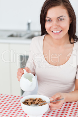 Portrait of a brunette pouring milk in her cereal