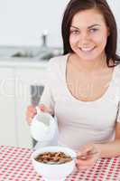 Portrait of a brunette pouring milk in her cereal