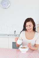 Portrait of a smiling woman pouring milk in her cereal