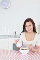 Portrait of a young woman pouring milk in her cereal