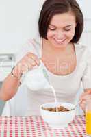 Beautiful dark-haired woman pouring milk in her cereal