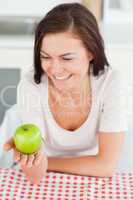 Laughing brunette looking at an apple