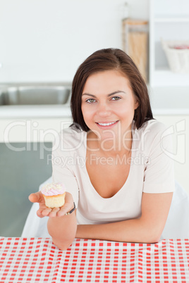 Smiling brunette showing a cupcake