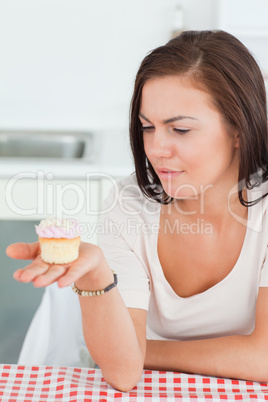 Cute brunette looking at a cupcake