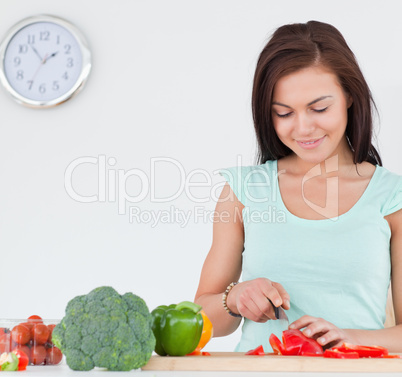 Smiling brunette slicing a pepper