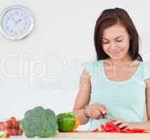 Smiling brunette slicing a pepper