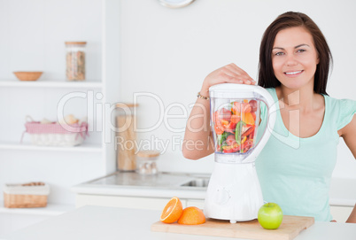 Dark-haired woman posing with a blender