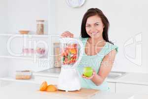 Happy woman with a blender and an apple