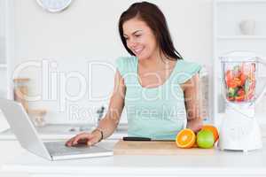 Young brunette with a laptop and fruits