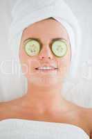 Smiling woman with cucumber slices on the face