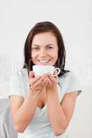 Portrait of a smiling dark-haired woman drinking tea