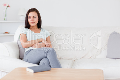 Smiling dark-haired woman sitting on her sofa