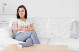 Smiling dark-haired woman sitting on her sofa