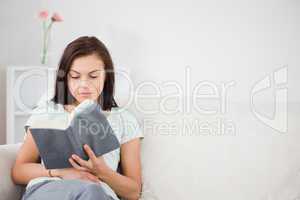 Cute dark-haired woman reading a book