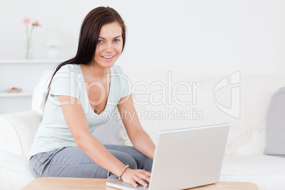 Smiling young woman typing on her laptop