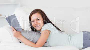 Smiling woman on a sofa with a book