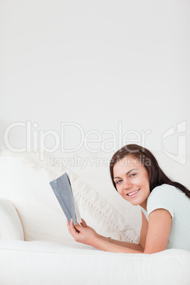 Portrait of a cute woman on a sofa holding a book