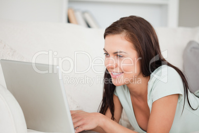 Close up of a cute brunette on a sofa using a laptop