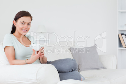 Young brunette sitting on a sofa with a cup of tea