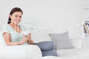 Young brunette sitting on a sofa with a cup of tea