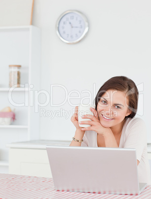 Portrait of a brunette using her laptop and having a tea