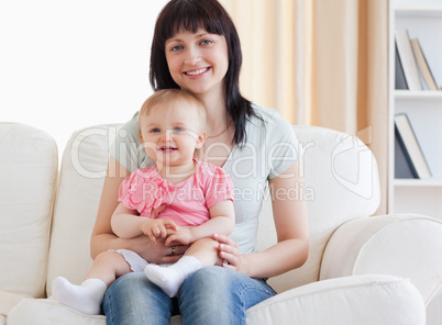 Beautiful woman holding her baby in her arms while sitting on a