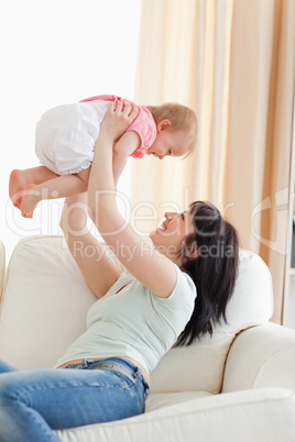 Gorgeous woman holding her baby in her arms while sitting on a s