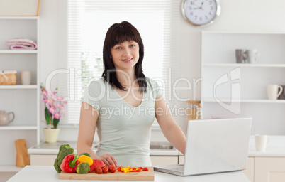 Lovely brunette woman relaxing with her laptop while standing