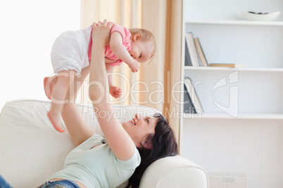 Charming woman holding her baby in her arms while sitting on a s