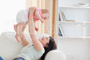 Charming woman holding her baby in her arms while sitting on a s