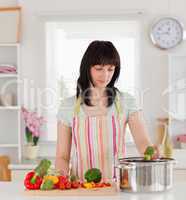 Pretty brunette woman posing while cooking vegetables