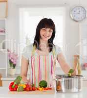 Beautiful brunette woman posing while cooking vegetables