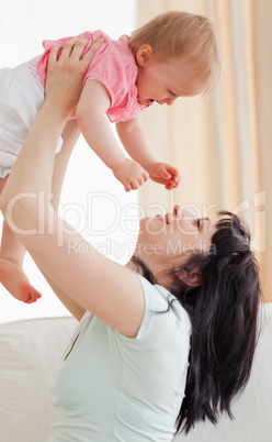 Cute woman holding her baby in her arms while sitting on a sofa