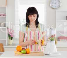 Attractive brunette woman pealing a banana while standing